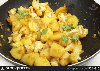 Aloo Gobi, potato and cauliflower sauteed with spices, a popular north-Indian side-dish, in a wok.
