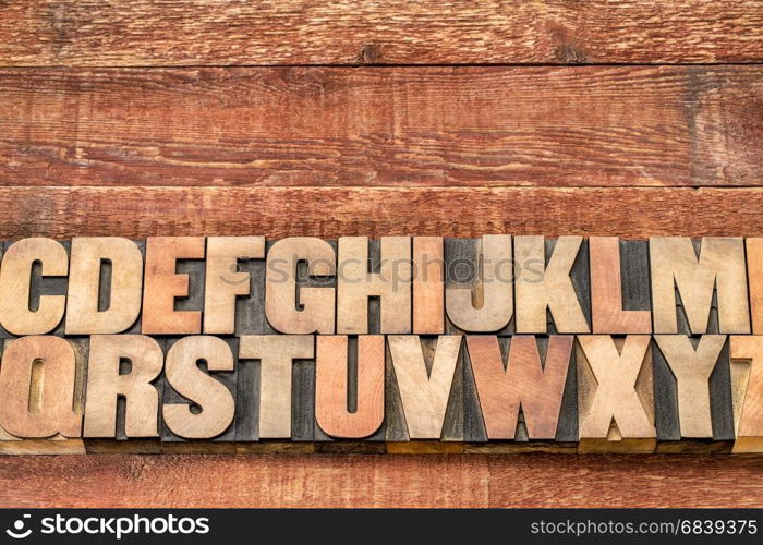 alphabet abstract in vintage letterpress printing blocks against rustic red painted barn wood with a copy space