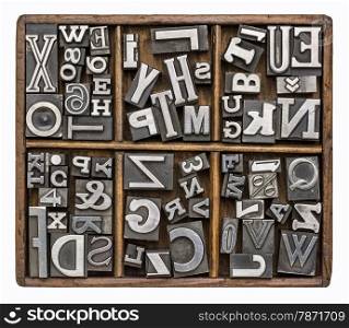 alphabet and other symbols in old metal type printing blocks in a rustic wooden typesetter box