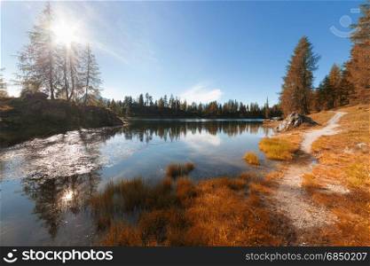Alpine fall colors mountain lake at sunny day. Dolomites Alps, Italy