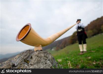 Alpine horn. A man plays in an alpine valley.