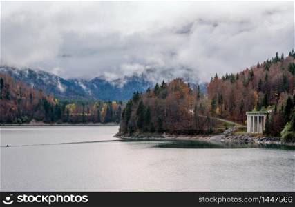 Alpine Sylvenstein Stausee lake on Isar river, Bavaria, Germany. Autumn overcast, foggy and drizzle day. Picturesque traveling, seasonal, weather, and nature beauty concept scene.