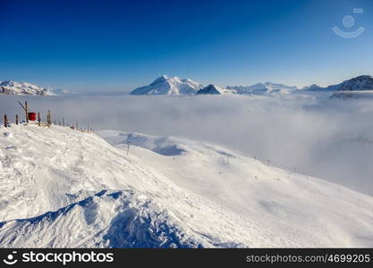 Alpine winter mountain landscape with low clouds. French Alps covered with snow in sunny day. Val-d'Isere, France