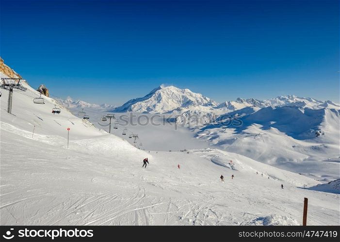 Alpine winter mountain landscape with ski lift and slopes. French Alps covered with snow in sunny day. Val-d'Isere, Alps, France