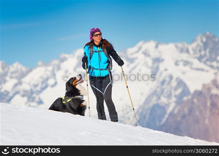 Alpinist girl on skis and sealskins alone with his dog faithful friend