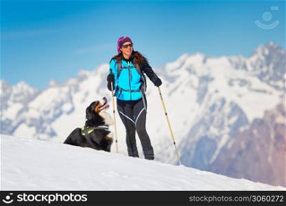 Alpinist girl on skis and sealskins alone with his dog faithful friend