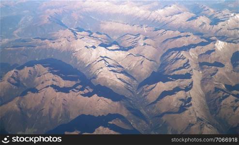 Alps, view of the mountains from the window of the plane. Land bending and nature concept.. Alps from plane window.