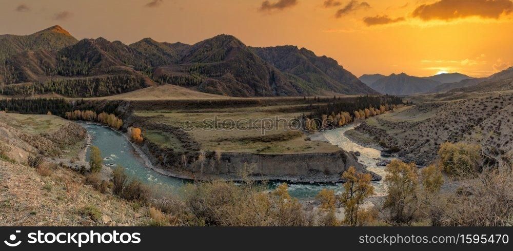 Altai mountains. Beautiful highland autumn panoramic landscape at sunset. Golden hour. Rocky foreground with golden trees and river. Beautiful golden sky and mountains as a background. Russia. Siberia. Altai mountains. Beautiful highland autumn panoramic landscape at sunset. Golden hour. Rocky foreground with golden trees and river. Beautiful golden sky and mountains as a background.Russia. Siberia