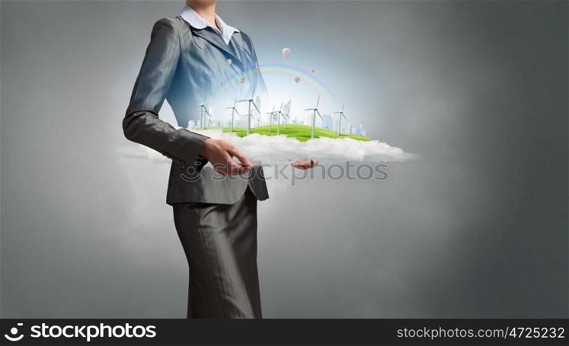Alternative energy concept. Wind turbines on meadow in woman hands against sky background