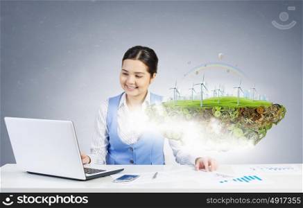 Alternative energy concept. Young smiling businesswoman sitting at table and working with 3d ecology project