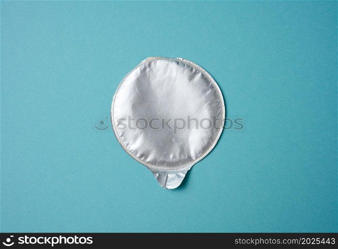aluminum round lid from under the package with chips on a blue background, flat lay