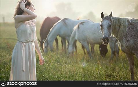 Aluring brunette lady walking next to the horses