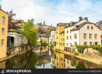 Alzette river bend with houses reflected in water and cathedral on the hill, Luxembourg city, Luxembourg