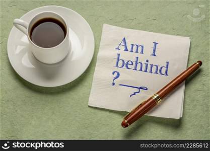 Am I my behind  A question written on napkin with a cup of coffee. Deadline, delay and stress concept.