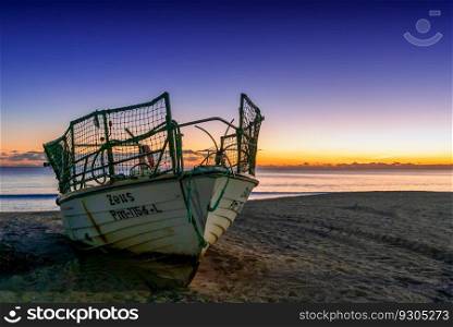Amarcao da Pera, Portugal - 30 December 2020: sunset at the Praia do Pescadores on the Algarve coast of Portugal with a small fishing boat on the beach