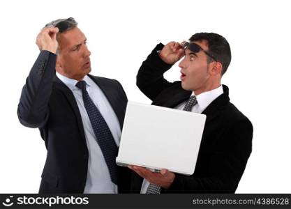 Amazed businessmen holding a laptop