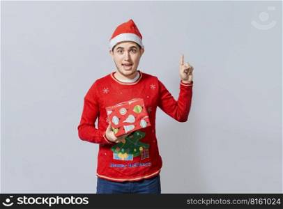 Amazed christmas man holding gifts pointing up. Surprised christmas man holding gifts and pointing up. Christmas man pointing a promo, Christmas man with surprised face holding a gift pointing up