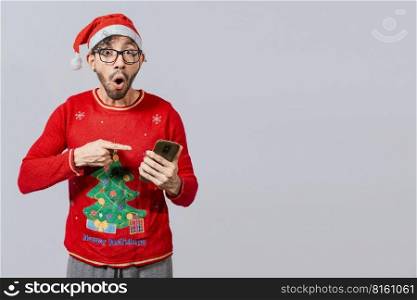 Amazed man pointing at christmas offer online, Guy pointing at christmas promotion on phone. Online Christmas special offers concept, amazed people pointing at a Christmas promotion on phone