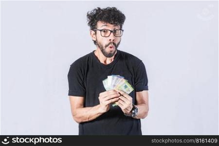 Amazed man with money in hand, man in glasses amazed with banknotes in hand, concept of man earning money