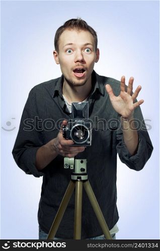 Amazed photographer taking pictures with medium-format camera, blue background