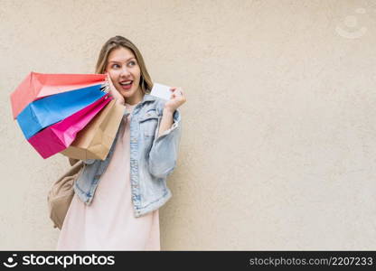 amazed woman standing with shopping bags credit card wall