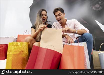 amazed young couple looking inside shopping bags