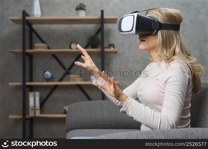 amazed young woman sitting sofa 3d goggles trying touch something invisible air
