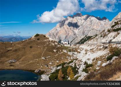 Amazing autumn rural landscape with yellow trees on foreground and mountain hills on background. Dolomite Alps, Italy