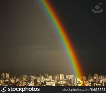 Amazing bright rainbow over city, picturescue beautiful view on the multicolored wonder of nature in rainy weather in the town, Lebanon. Amazing bright rainbow over city