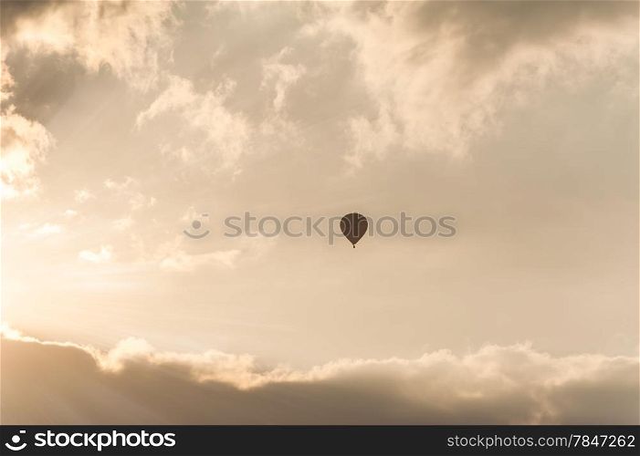 Amazing colors of sunrise with sunbeams over clouds and hot air balloon silhouette