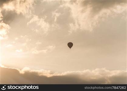 Amazing colors of sunrise with sunbeams over clouds and hot air balloon silhouette
