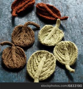Amazing craft products from yarn, group knitted winter leaf on wooden background, beauty alder leaf with vintage tone