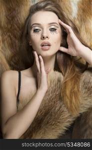 amazing fashion portrait of young sexy female with winter style and creative make-up. Covering her breast with fluffy fur and posing on fur background