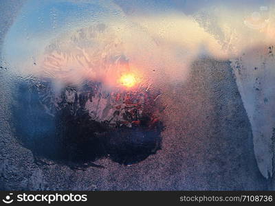 Amazing ice patterns and water drops on a frozen window pane on a sunny winter morning, closeup natural texture