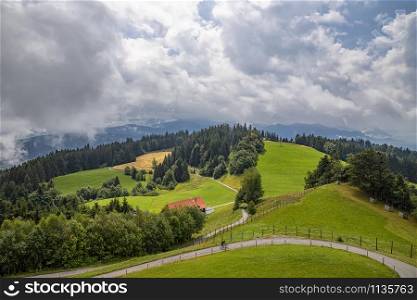 Amazing idyllic landscape with green rolling hills, road, and farmhouses in the mountain of Austria