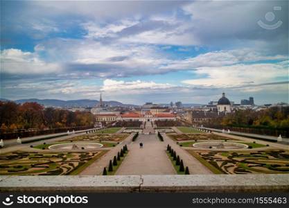 Amazing landscape with view to Unteres Belvedere and garden parterre of regular planting of trees and flowers in Vienna, Austria on a background of autumn cloudy sky.. Landscaping view to Unteres Belvedere and regular parterre in Vienna.