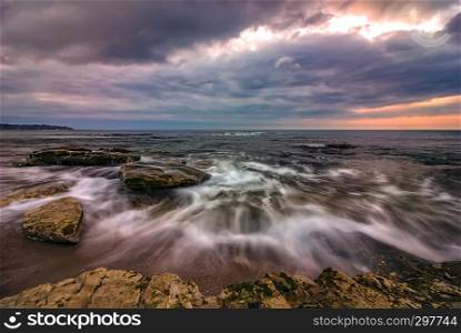 Amazing long exposure seascape with motion blur and flowing waves at the rocks.