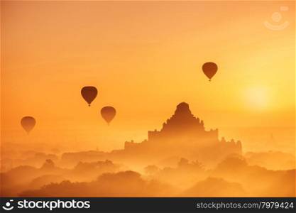 Amazing misty sunrise colors and balloons silhouettes over ancient Dhammayan Gyi Pagoda. Architecture of old Buddhist Temples at Bagan Kingdom. Myanmar (Burma). Travel landscapes and destinations