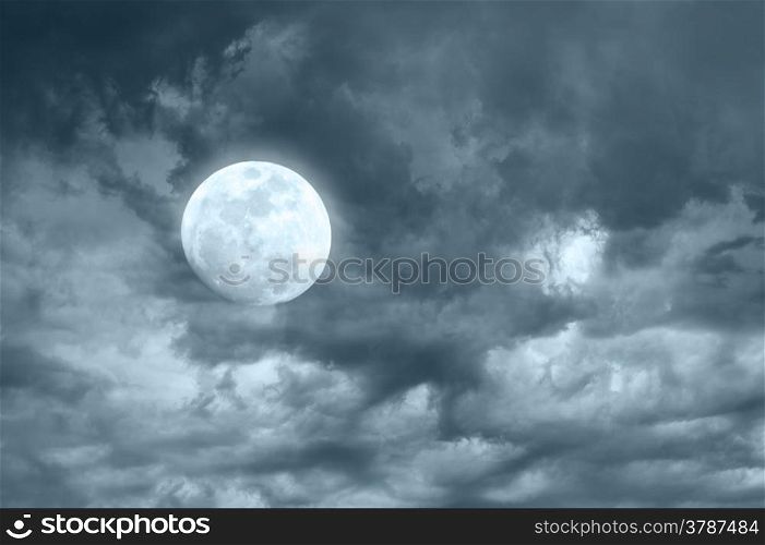 Amazing night sky with shining full moon and dramatic clouds