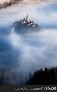 amazing panorama of Lake Bled Blejsko Jezero on a foggy morning with the Pilgrimage Church of the Assumption of Maria on a small island and Bled Castle and Julian Alps in backgroud