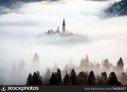 amazing panorama of Lake Bled Blejsko Jezero on a foggy morning with the Pilgrimage Church of the Assumption of Maria on a small island and Bled Castle and Julian Alps in backgroud