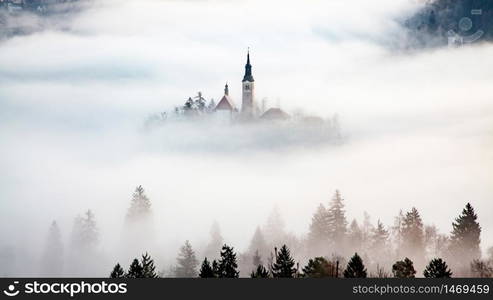 amazing panorama of Lake Bled Blejsko Jezero on a foggy morning with the Pilgrimage Church of the Assumption of Maria on a small island and Bled Castle and Julian Alps in backgroud