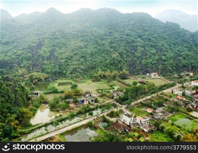 Amazing panorama view of the rice fields, limestone rocks and mountaintop Pagoda from Hang Mua Temple at the early rainy morning. Ninh Binh, Vietnam. Travel landscapes and destinations background