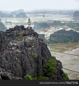 Amazing panorama view of the rice fields, limestone rocks and mountaintop Pagoda from Hang Mua Temple at the early rainy morning. Ninh Binh, Vietnam. Travel landscapes and destinations background