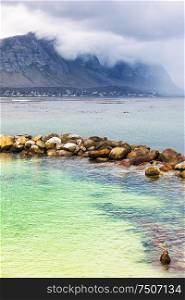 Amazing peaceful view on the Betty&rsquo;s Bay, beautiful blue-green lagoon with clear water, mountains in the fog near shore, Atlantic Ocean, South Africa