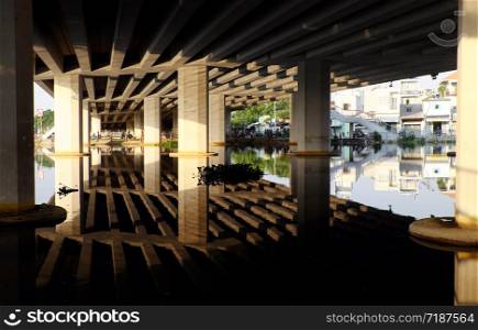 Amazing scene under bridge with reflection wonderful shadow, shape, lines and curve with glean from sunlight on surface water of river at Ho chi Minh city, Vietnam on day