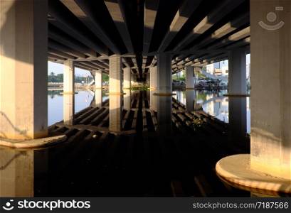 Amazing scene under bridge with reflection wonderful shadow, shape, lines and curve with glean from sunlight on surface water of river at Ho chi Minh city, Vietnam on day