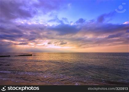 Amazing scenic view of colorful sky with sun rays over the sea.