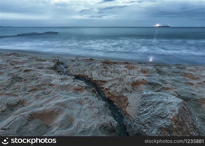 Amazing seascape with a light ray from the ship and a small brook flowing into the sea