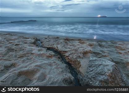 Amazing seascape with a light ray from the ship and a small brook flowing into the sea